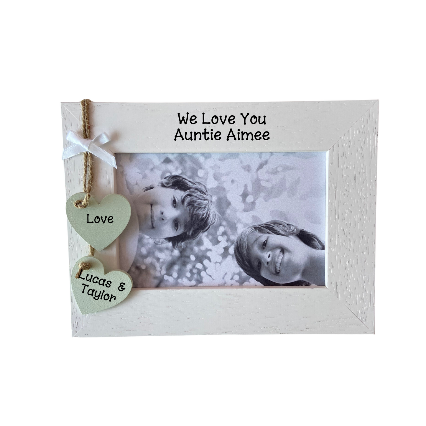 Image shows we love our auntie photo frame, including two hanging hearts one saying love and one with the niece(s) and/or nephew(s) names, also a small white bow placed above the hearts, bling can be added