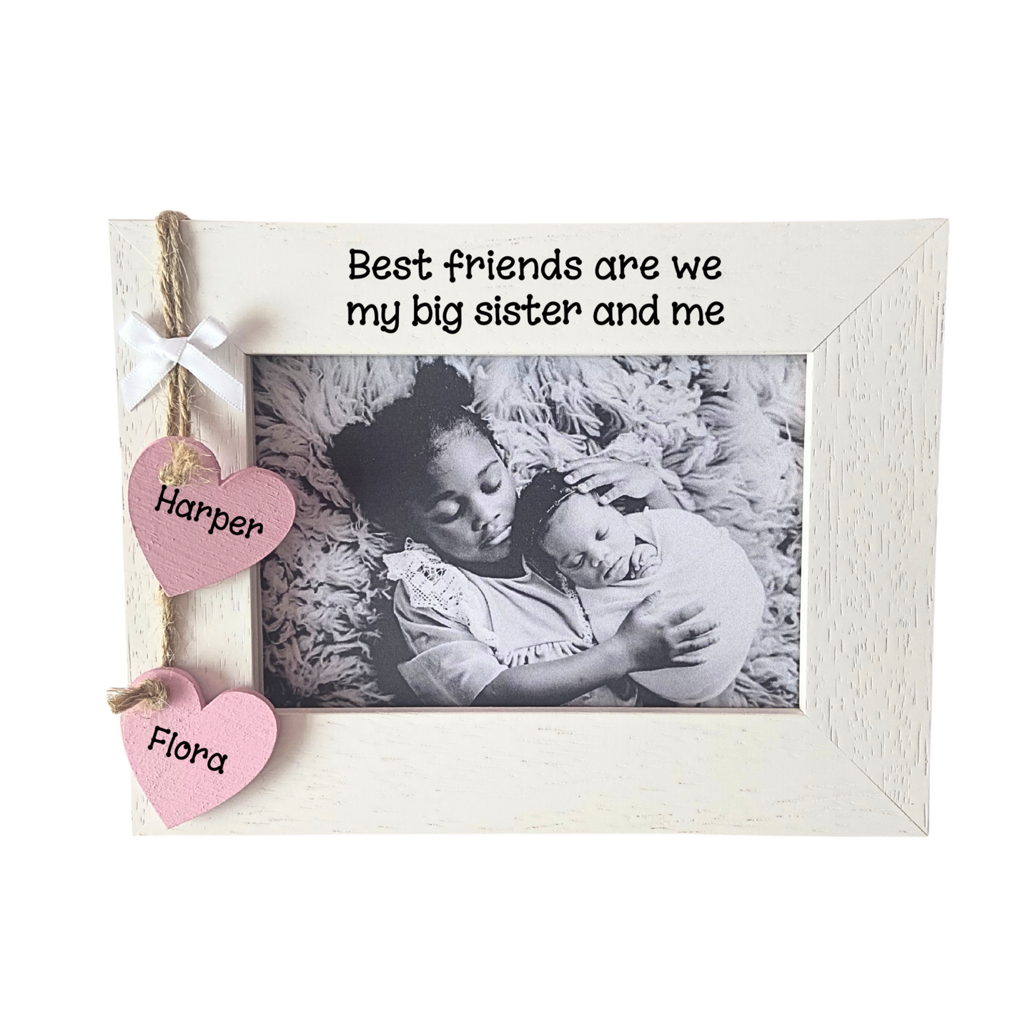 Image shows wooden photo frame for big sister, includes two hanging hearts with sisters names also a small white bow placed above. Bling can be added.