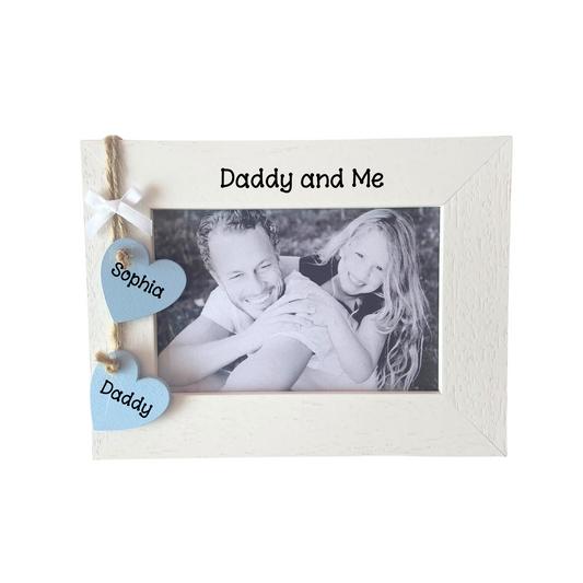Image shows daddy and me photo frame available in portrait and landscape. Includes two hanging hearts on the side with daddy and the childs name, also with a small white bow and bling if wanted.