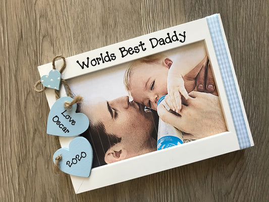 Image shows worlds best daddy photo frame with gingham down the side, consists of two hanging hearts with the child's name and year, also a small dotted heart placed above.
