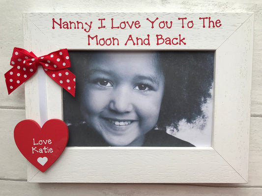 Image shows nanny photo frame, including a wooden heart with grand child's name and a white ribbon attached to dotted bow.